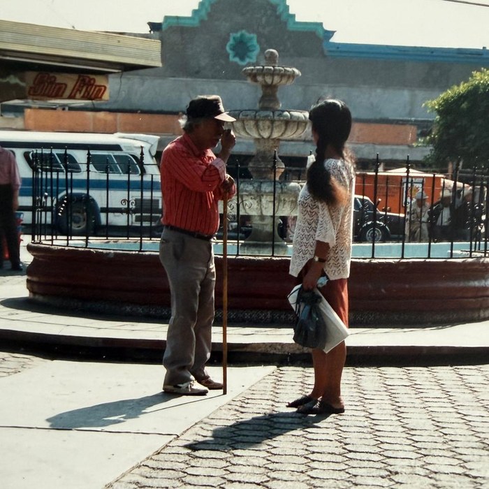 Tijuana, 1991: an older man with a cane talks to a young woman at a fountain